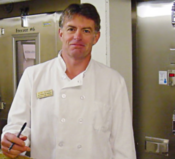 a chef standing next to a freezer door