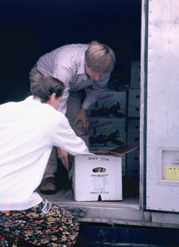 a chef checking out a farmer's box of produce in a semi trailer